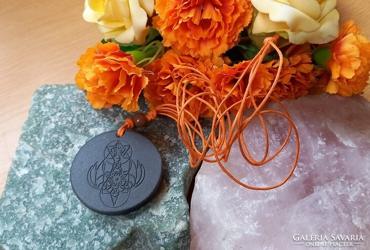Amulet engraved in volcanic stone, talisman pendant on a string with magical symbols