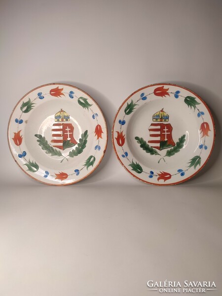 A pair of hard ceramic painted folk wall plates marked Hóllóháza with an old coat of arms