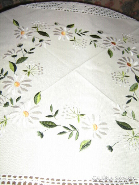 A beautiful hand-crocheted tablecloth with a daisies embroidered with floral edges