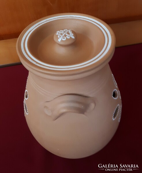 An unglazed ceramic pot with a lid and pierced sides