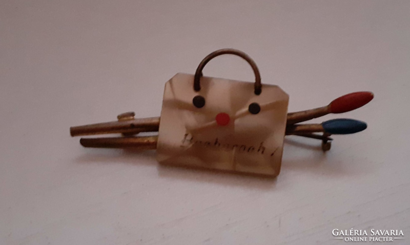 A small mother-of-pearl bag-shaped brooch holding a paint brush made with retro handwork