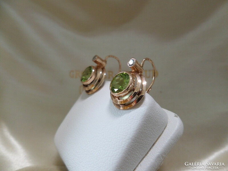 A pair of gold earrings with olivine and brils