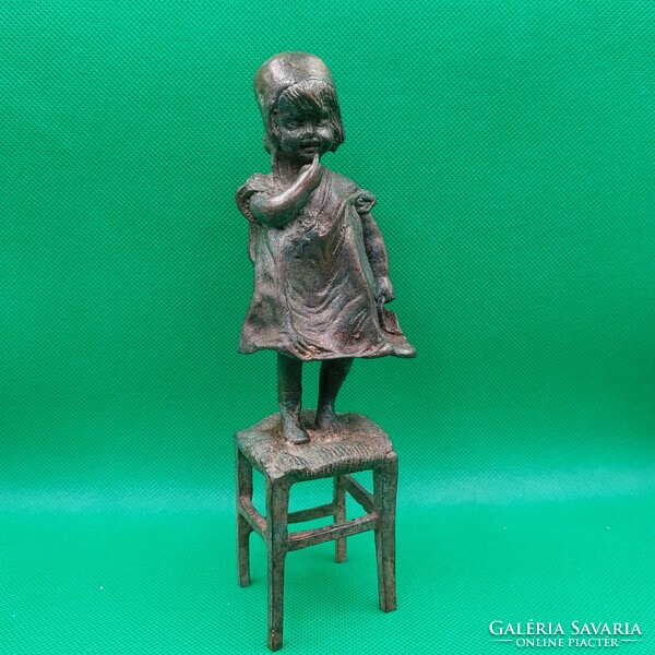 Statue of a little girl standing on a chair