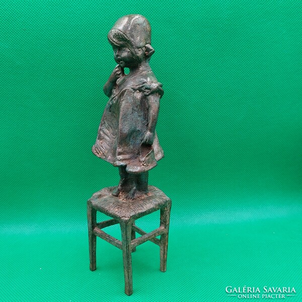 Statue of a little girl standing on a chair