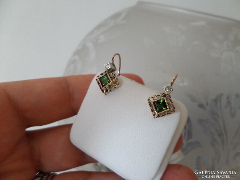 A pair of gold earrings with green tourmalines and brils