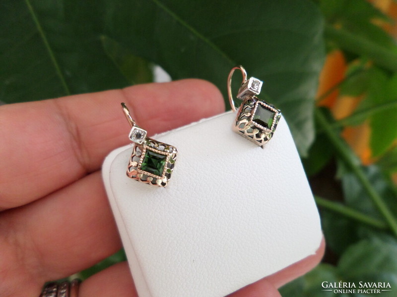 A pair of gold earrings with green tourmalines and brils