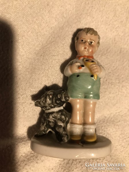 A small porcelain statue of a child eating a cherry with a dog