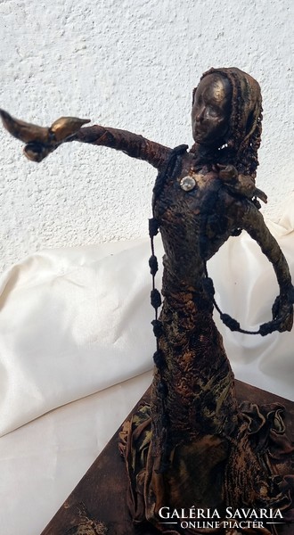 The handcrafted textile sculpture waiting for peace is made of recycled materials and is black-bronze in color