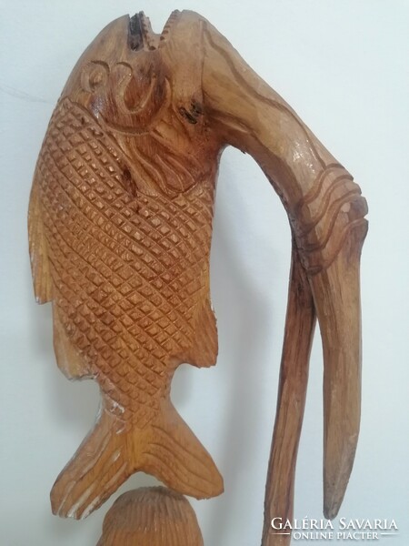 A large wooden statue of a fisherman with the caught fish on his harpoon