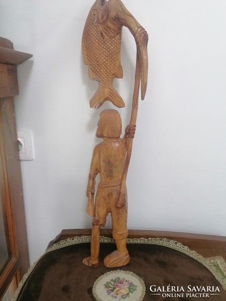 A large wooden statue of a fisherman with the caught fish on his harpoon