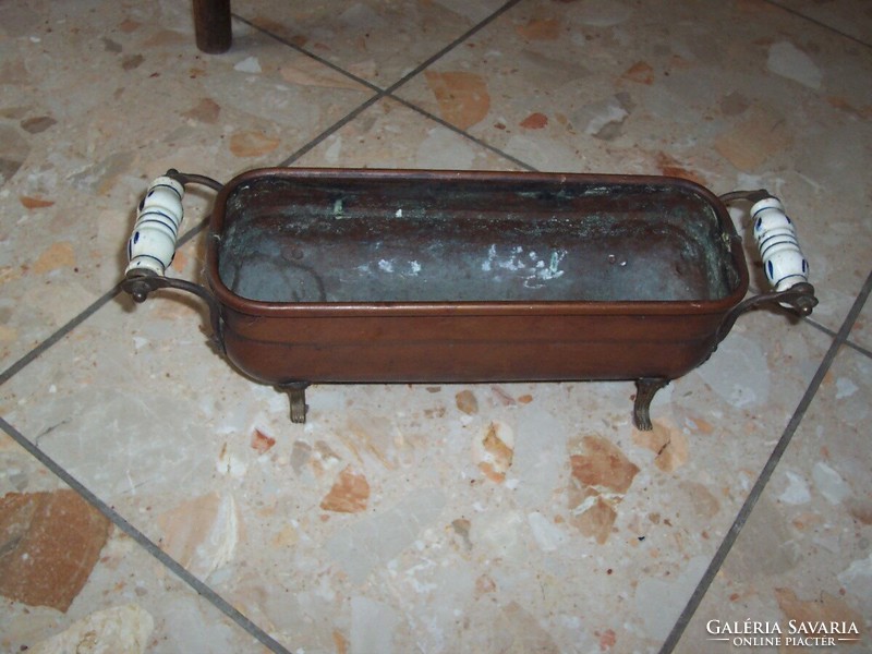 Red copper flowerpot with porcelain handles standing on beautiful legs