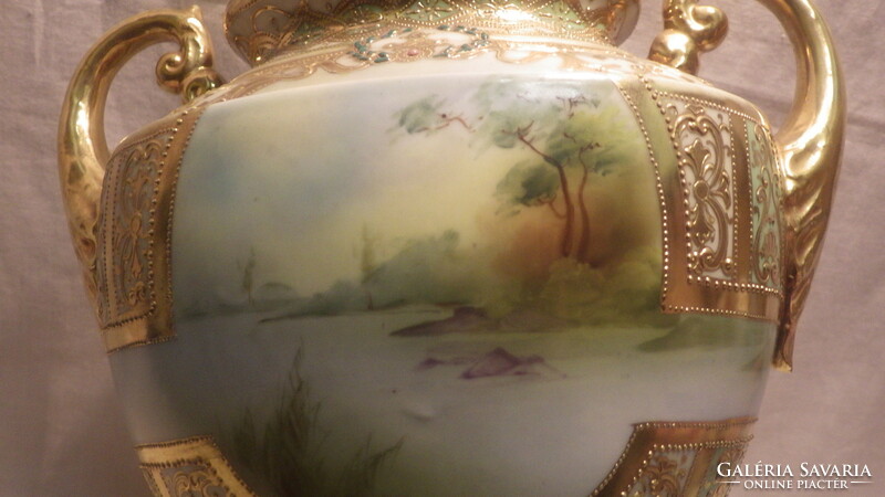 An antique porcelain vase with a richly decorated painting in sumptuous gold