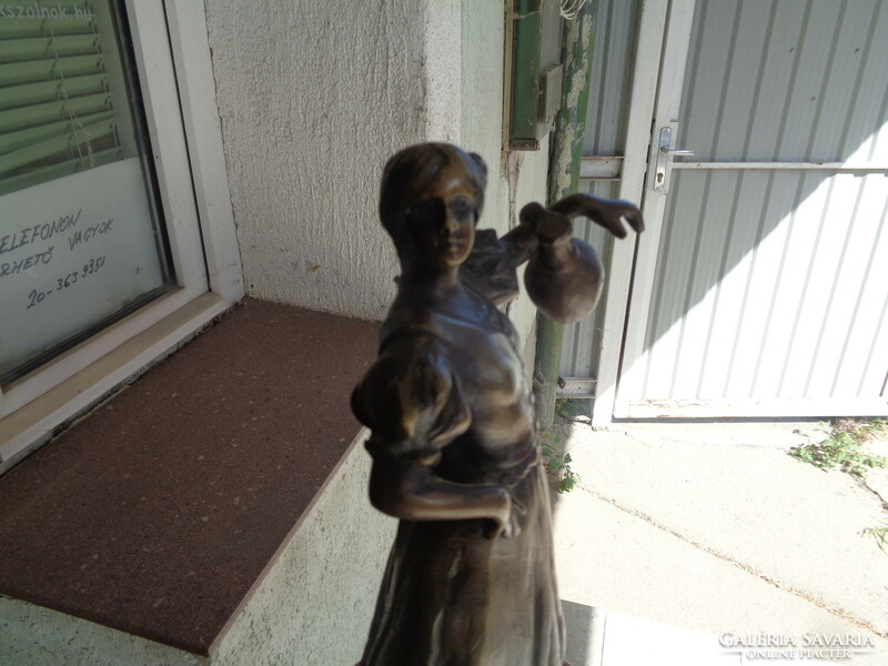 Bronz szobor, korsót tartó asszony