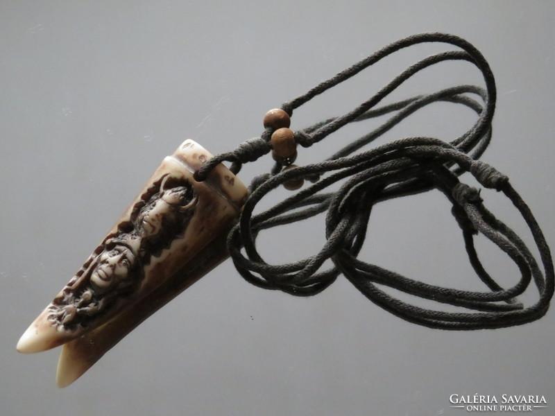 A carved bone of a tribal nature? Pendant on a strap decorated with wooden beads.