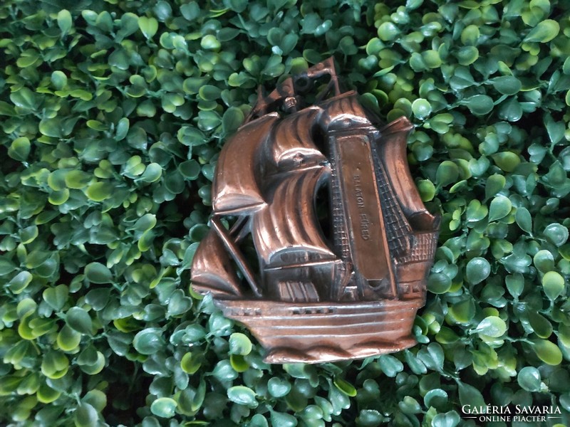 Copper, bronze-colored wall ornament depicting a sailing ship with the inscription Balatonfüred