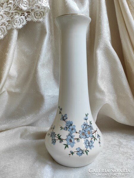 A tall aquincum porcelain vase with a long neck and a tree branch pattern with charming blue flowers