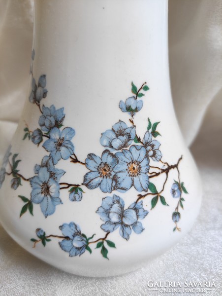 A tall aquincum porcelain vase with a long neck and a tree branch pattern with charming blue flowers