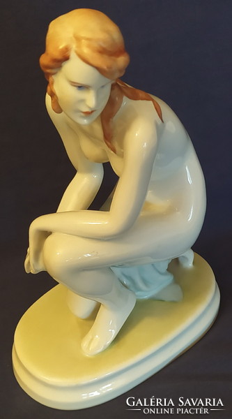 Statue of a female nude kneeling on an antique Zolnay pedestal