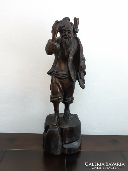 A hardwood statue depicting an Eastern sage
