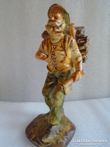 A small curio of a man carrying firewood with an ax in his hand, showcase condition, brilliant color scheme
