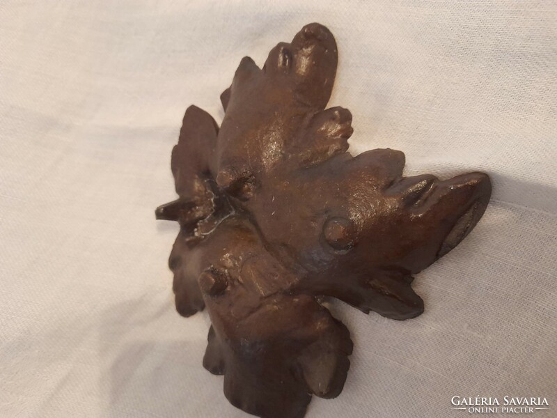 Old metal work, perhaps an ornament in the shape of a bronze grape leaf, an ashtray