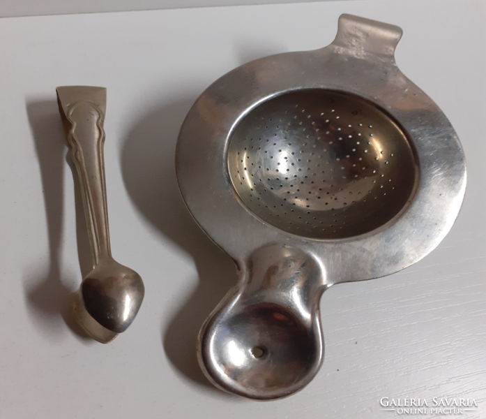 An alpaca tea strainer with a handle that can be placed on the top and rim of an old tea mug with sugar tweezers