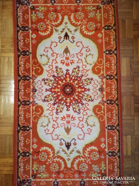 A small machine-made Persian carpet in an orange tone, a legacy of Inke László and Márta