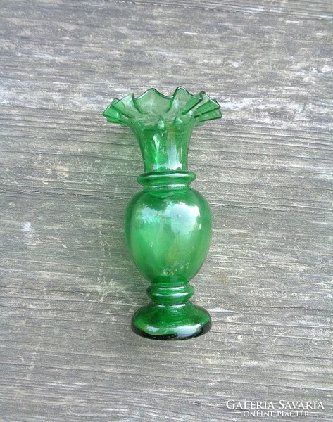 Old green broken glass vase with ruffled edges