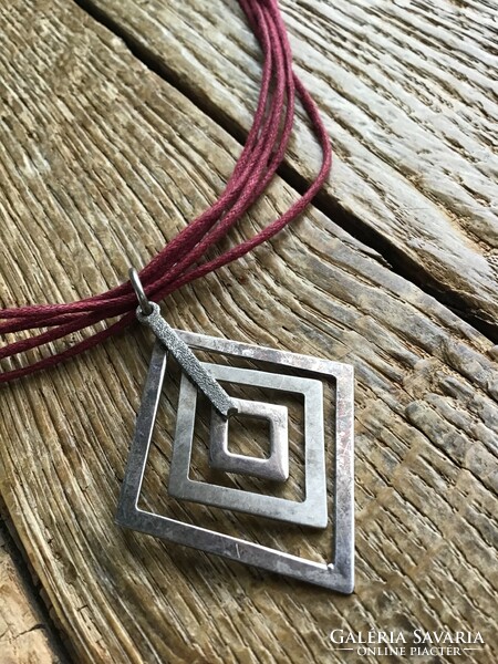 Silver pendant with silver fittings on a cord necklace