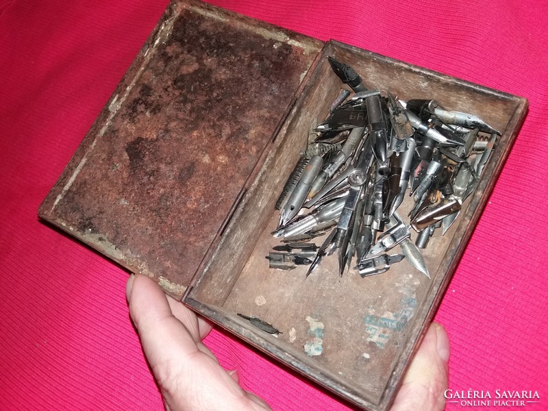 Antique tin box with old contents on a large pile of pen nibs along with pictures