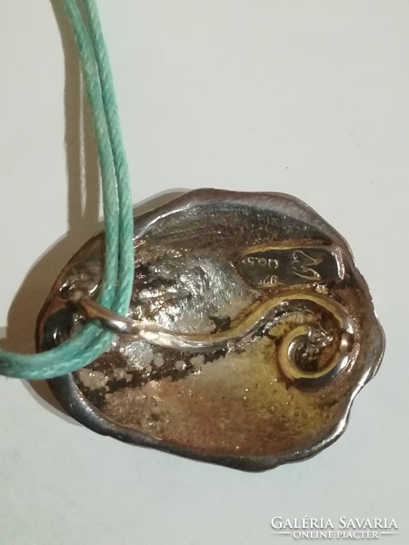 Enameled silver pendant on the outside, and a silver mount on a waxed cord.