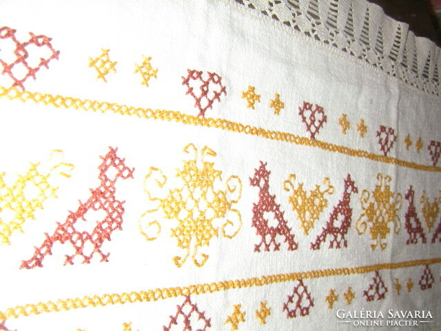 A beautiful folk traditional cross-stitch hand-embroidered tablecloth with a lace edge