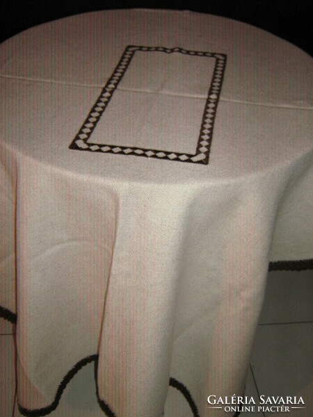 A beautiful cappuccino-colored brown hand-embroidered woven tablecloth with a crocheted edge