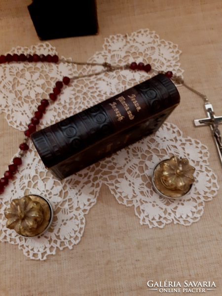 Old nun's heirloom prayer book with buckle, rosary on a lace tablecloth with a gift candle