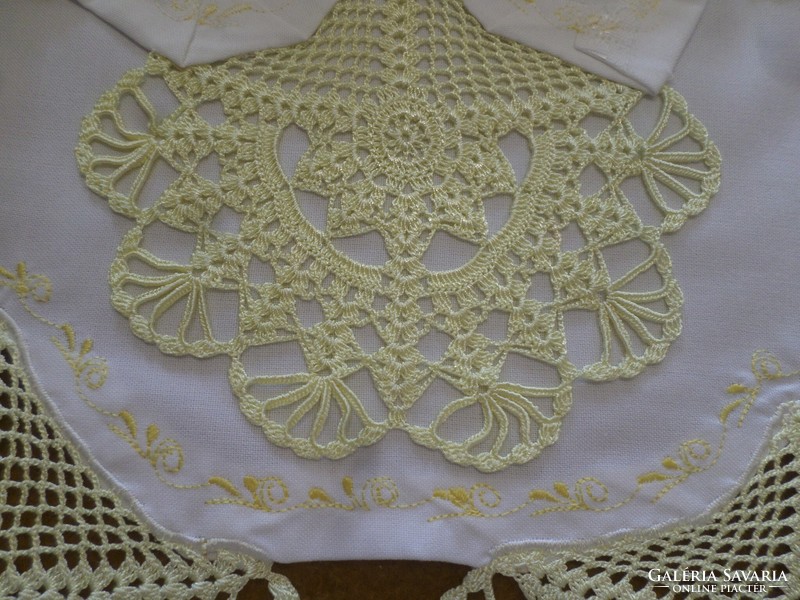 A large snow-white tablecloth with pale yellow crocheted lace and embroidery on the edge.
