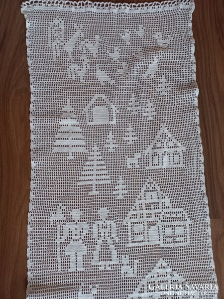 Snow-white crocheted curtain with a farm scene