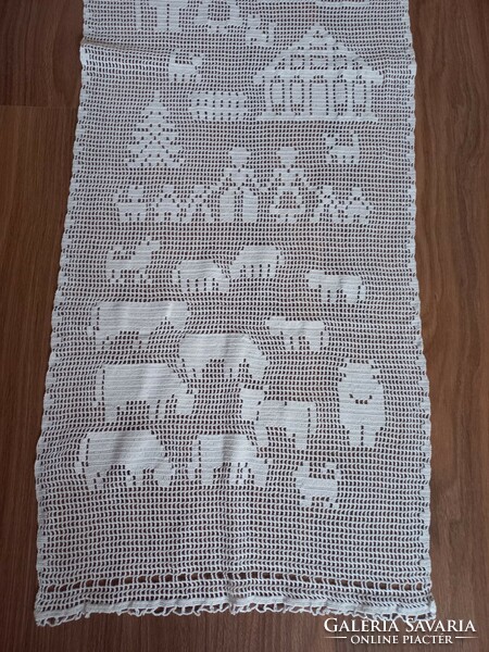 Snow-white crocheted curtain with a farm scene