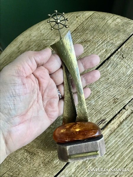 Old copper statue on a wooden base decorated with a large amber stone