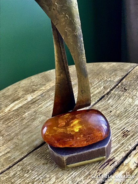 Old copper statue on a wooden base decorated with a large amber stone