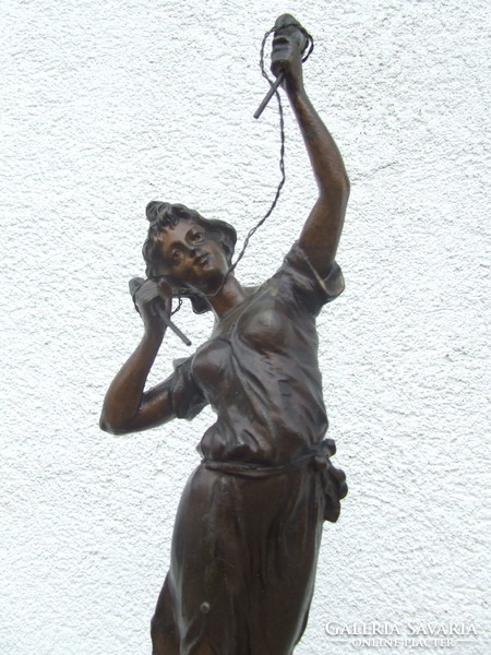 A spaiater statue of a woman examining electricity