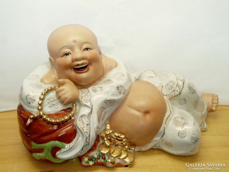 A giant reclining, laughing Buddha made of china, richly gilded, with an open mouth