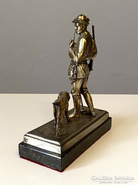 Antique metal statue of a pipe-smoking hunter and a retriever on a marble base