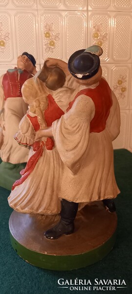 Two old, large-scale painted statues. Dancing peasants, watering cans.