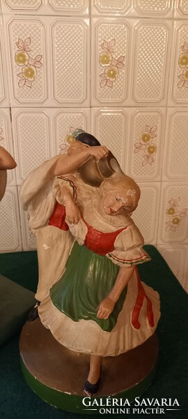 Two old, large-scale painted statues. Dancing peasants, watering cans.
