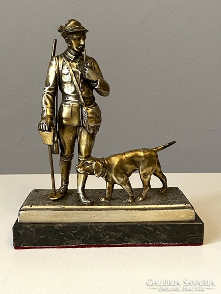 Antique metal statue of a pipe-smoking hunter and a retriever on a marble base