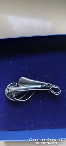 Silver colored brooch.