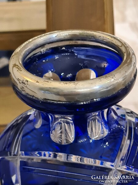 A polished blue old glass vase with a silver rim