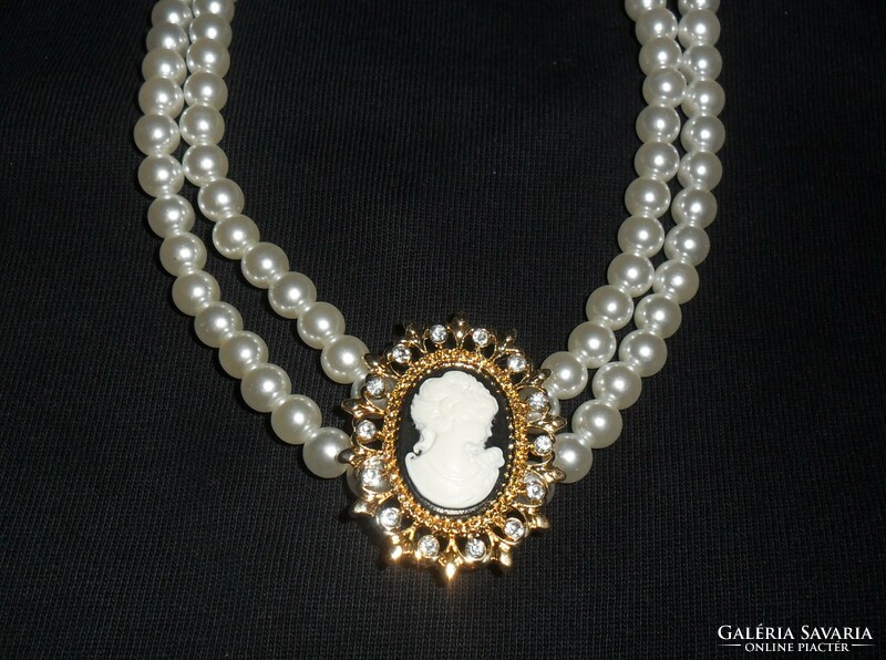 A beautiful, shiny double row of pearls, with a pendant decorated with a cameo and rhinestones.