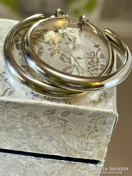 A pair of larger silver hoop earrings with a clean shape