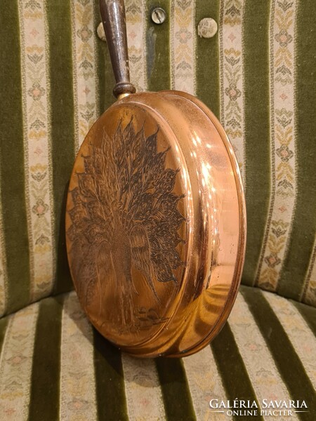 Antique red copper pan carved with a peacock shape with a wooden handle